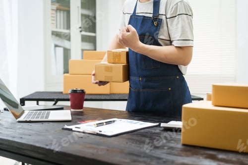 Preview: A man is working at his desk, preparing parcel boxes for shipment. He checks packs items carefully
