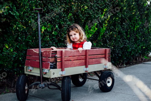 Preview: Portrait of female toddler sitting in garden cart