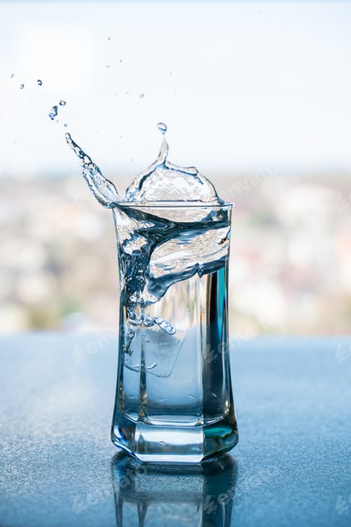 Preview: Splashing Water in a Glass Captured Against a Blurred City Backdrop During Daylight