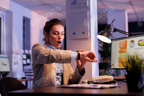 Preview: Surprised businesswoman checking time on wristwatch