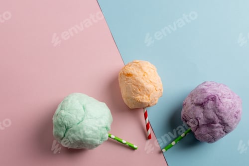 Preview: Horizontal image of three sticks of colourful homemade candy floss, on blue and pink with copy space