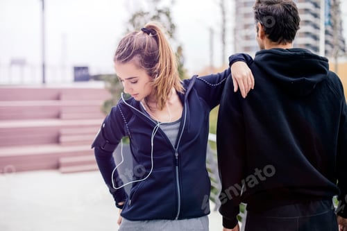 Preview: Male coach helping young woman exercising at outdoors