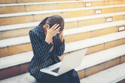 Preview: Business woman stressed while using laptop sits on the steps. Business people concept.