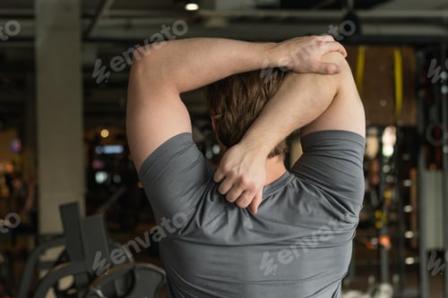 Preview: Athlete or caucasian young sporty man doing stretching back and arms. Back View