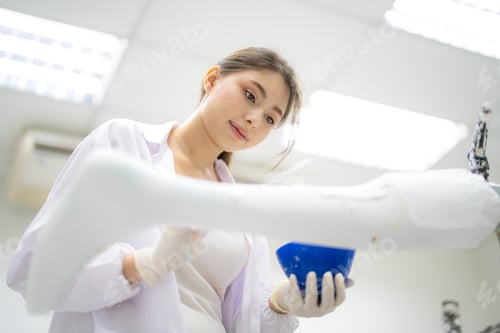 Preview: Female physiotherapist in workshop molding dummy of prosthetic human body parts.