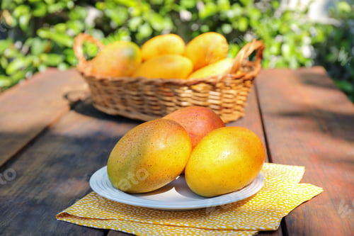 Preview: Plate with tasty mangoes on wooden table outdoors