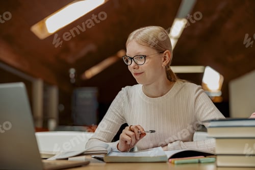Preview: Young talented female student studying on laptop sit in university library