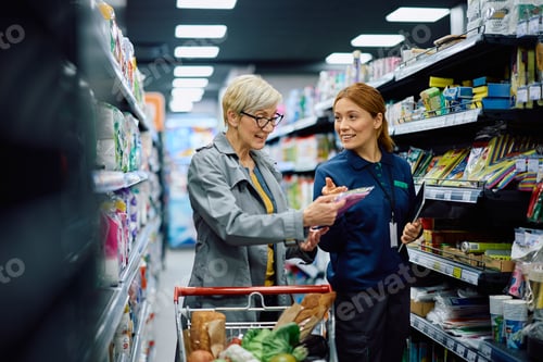Preview: Happy senior woman communicating with female worker while buying in a supermarket.