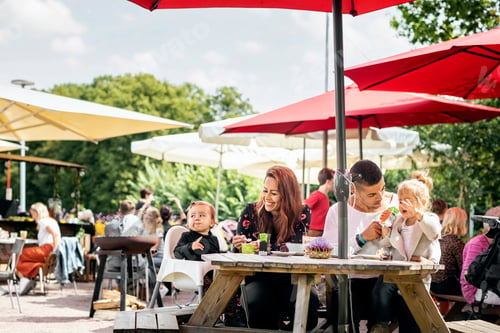 Preview: Family with young daughters relaxing in outdoor restaurant