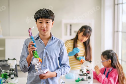 Preview: boy is holding model skeleton in classroom