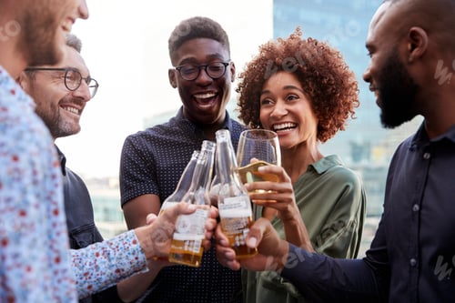 Preview: Happy creative business colleagues having a drink after work raise glasses to make a toast