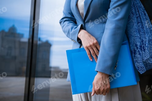 Preview: Business woman with folder in hand near office building