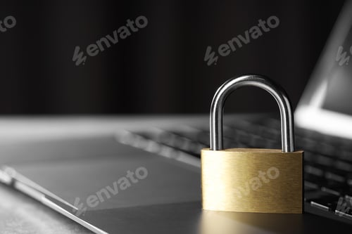 Preview: Cyber safety. Metal padlock and laptop on table, closeup. Space for text