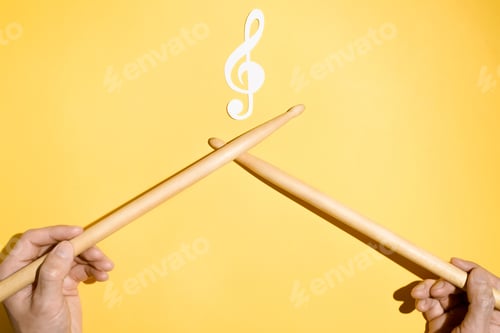 Preview: Drummer concept. Male hands holding drumsticks and a paper treble clef and musical treble clef. Flat
