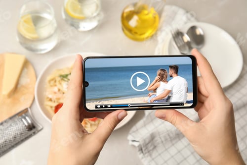 Preview: Woman watching video on mobile phone at table during lunch, closeup