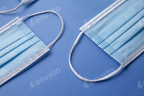 Preview: High angle closeup shot of medical masks placed on a blue b\