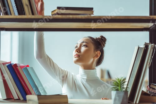Preview: beautiful young asian woman choosing books in library