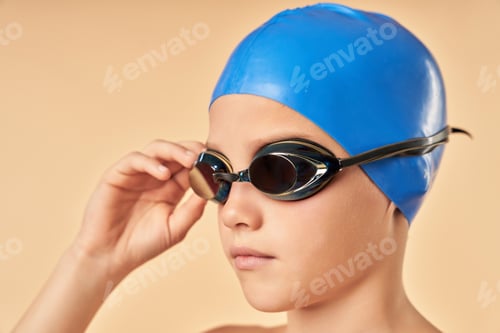 Preview: Cute boy swimmer standing against light orange background