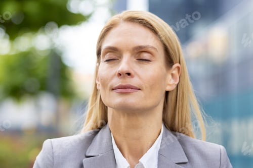 Preview: Relaxed businesswoman taking a break outdoors with eyes closed, finding inner peace