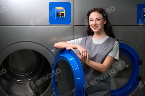 Preview: Woman dry-cleaning service worker standing near big industrial machine