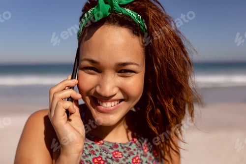 Preview: Front view of beautiful happy Mixed-race woman talking on mobile phone on beach in the sunshine