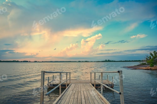 Preview: A wooden dock leading out into a lake at sunset with a beautiful sky above