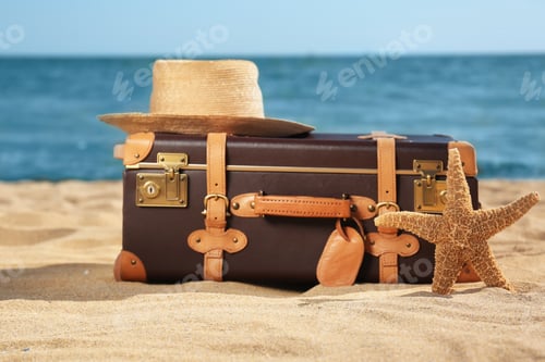 Preview: Suitcase, hat and starfish on sand near sea. Beach accessories