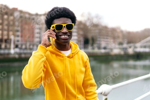 Preview: Smiling African Young Man with Sunglasses Talking on Phone