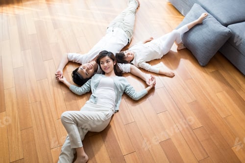 Preview: Happy young family resting on wooden floor