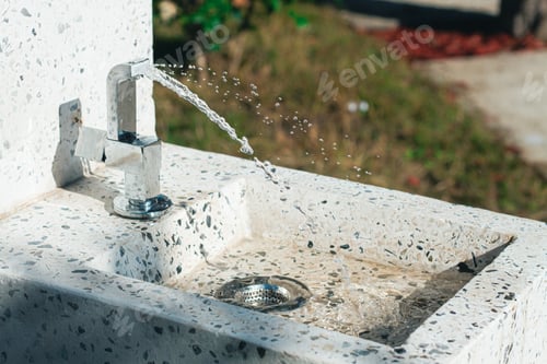Preview: Water flowing from a clean tap fountain at a park in bright sunlight during a sunny day