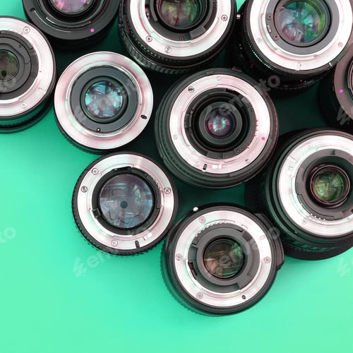 Preview: Several photographic lenses lie on a bright turquoise background. Copy space