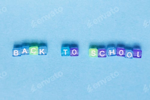 Preview: The inscription back to school made by multicolor plastic cubes on a blue background.