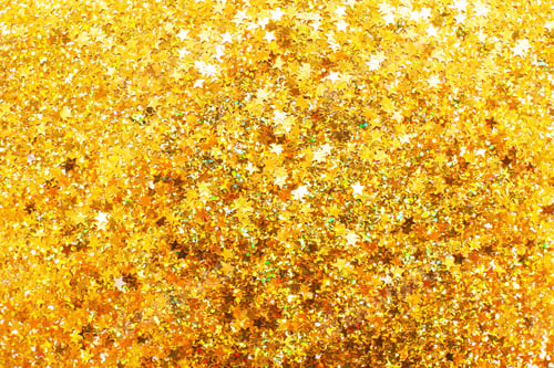 Preview: Glittering background of golden sequins in form of stars closeup. Sparkle festive texture.