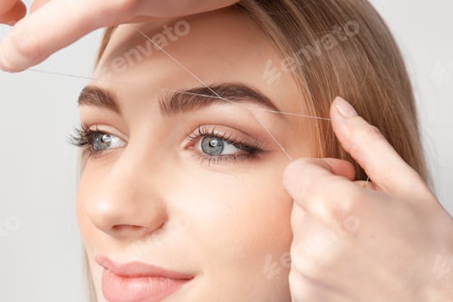 Preview: Young woman having professional eyebrow correction procedure in beauty salon