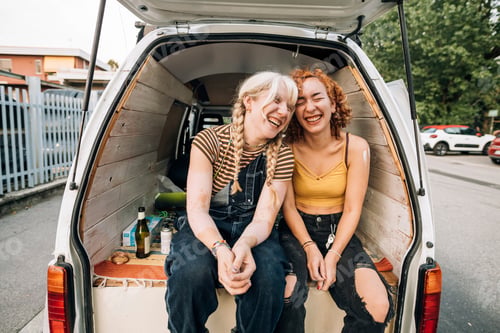 Preview: Two friends sharing a laugh in the back of a van on a road trip