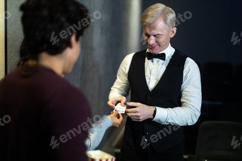 Preview: Cinema usher checking tickets of young moviegoer at entrance