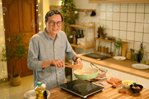 Preview: Joyful smiling middle aged man preparing a meal in a cozy kitchen.