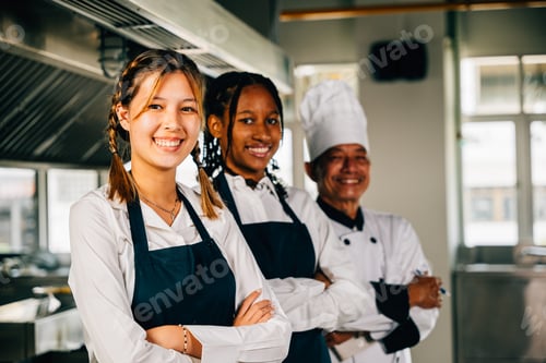 Preview: Chefs in uniform smiling at the camera in a professional kitchen. Illustrating expertise teamwork