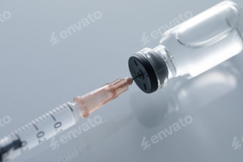 Preview: Closeup shot of a covid19 vaccine bottle and a needle on a gray background - covid19 concept