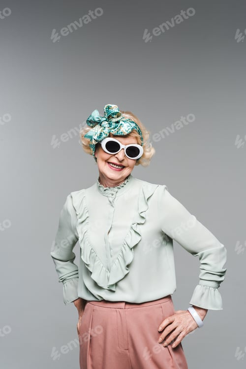 Preview: happy senior woman in stylish headband and sunglasses isolated on grey