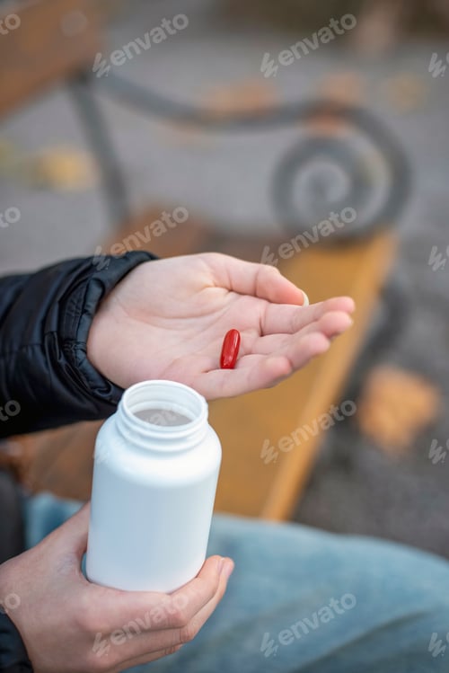 Preview: Woman Holds Red Pill While Sitting on Bench