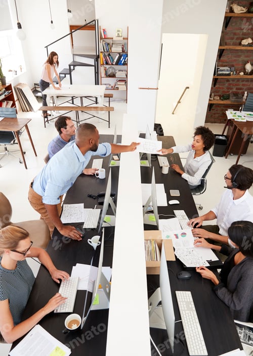 Preview: Man passing document in busy open plan office, vertical