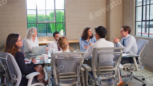 Preview: Business Team Meeting Sitting Around Table In Modern Office Discussing Documents