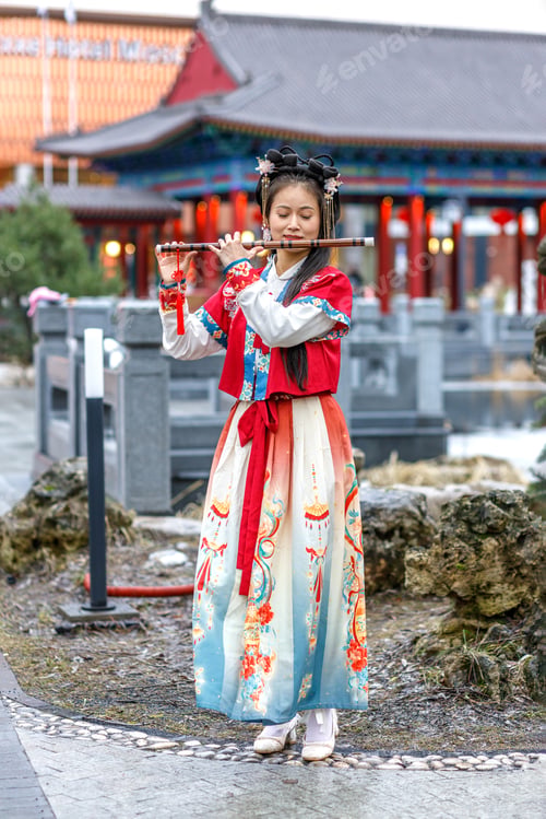 Preview: A woman in red Chinese costume walks in the park,plays the bamboo flute.Celebrating Chinese New Year