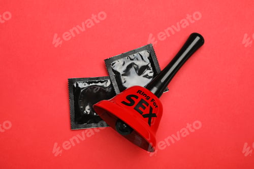 Preview: Sex bell and condoms on red background, top view
