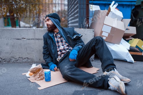 Preview: Dirty beggar with food sitting at the trashcan