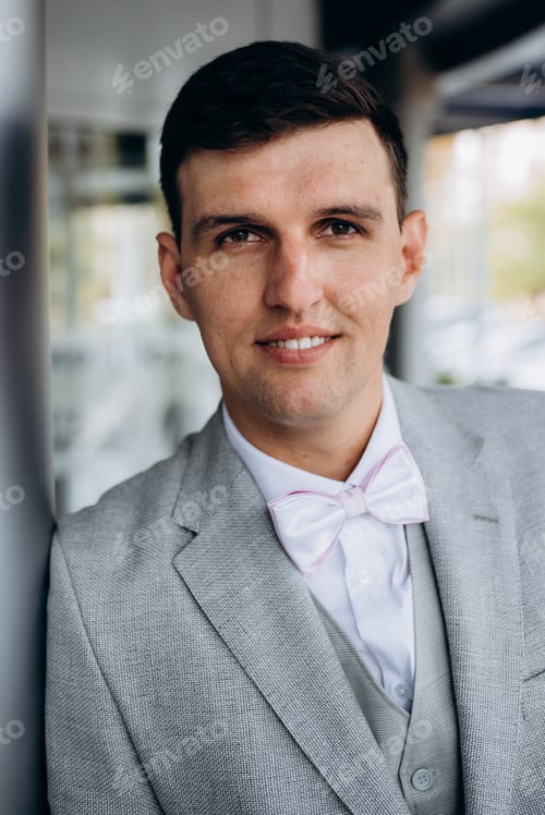 Preview: portrait of a groom in a suit and white bow