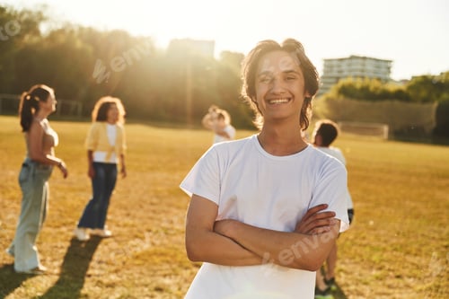 Preview: Guy is standing in front of other people. Young friends are having fun on the field