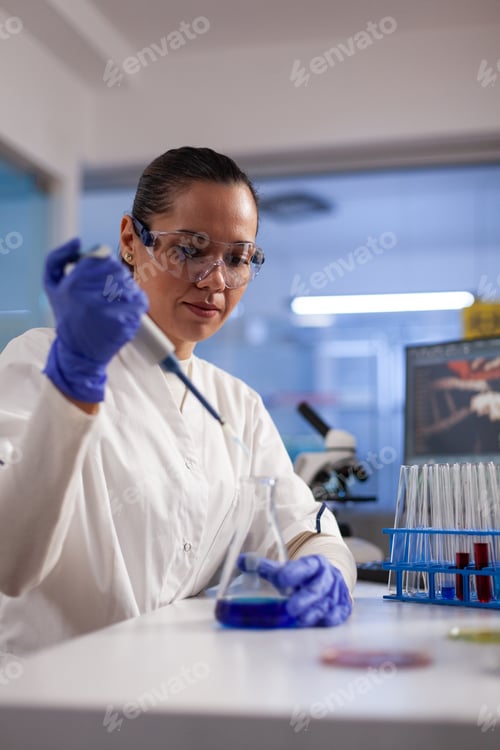 Preview: Physician researcher dropping liquid in medical glassware using micropipette