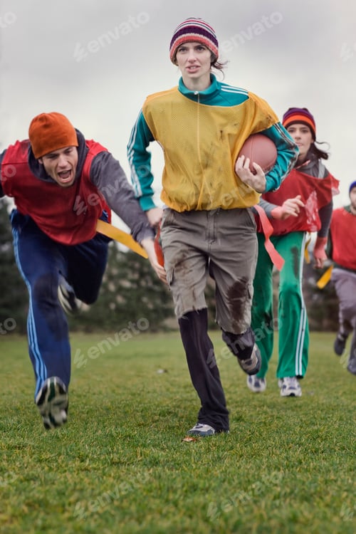 Preview: Caucasian woman running with the football in an non-contact flag football game.
